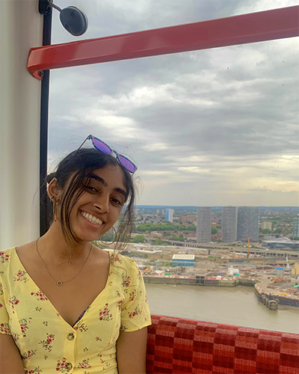 Vasu sits in a London cable car over the Thames River with a view of London through the window